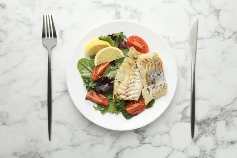 Tasty cod cooked served with salad on white marble table, flat lay Stock Photos