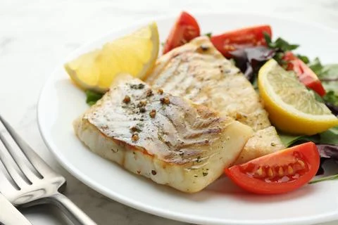 Tasty cod cooked served with salad on white table, closeup Stock Photos