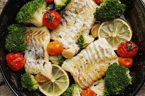Tasty cod cooked with vegetables in frying pan. top view Stock Photos