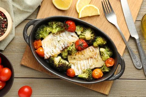 Tasty cod cooked with vegetables served on wooden table, flat lay Stock Photos