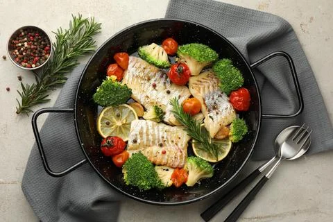 Tasty cod cooked with vegetables served on grey table, flat lay Stock Photos