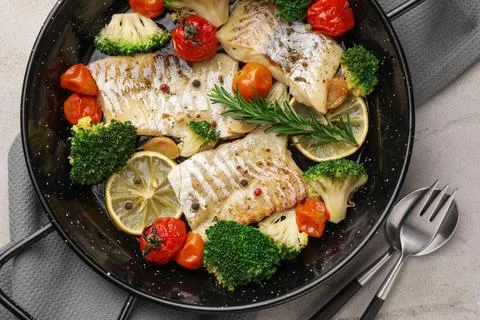Tasty cod cooked with vegetables served on grey table, flat lay Stock Photos