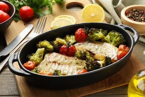 Tasty cod cooked with vegetables served on wooden table Stock Photos