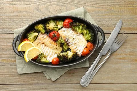 Tasty cod cooked with vegetables served on wooden table, flat lay Stock Photos