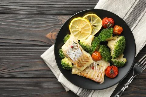 Tasty cod cooked with vegetables served on wooden table, flat lay. Space fo.. Stock Photos