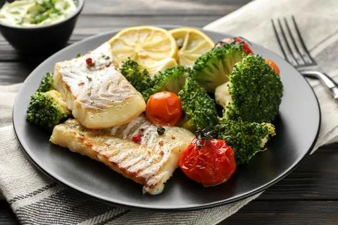 Tasty cod cooked with vegetables served on table Stock Photos