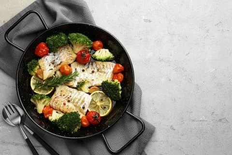 Tasty cod cooked with vegetables served on grey table, flat lay. Space for te Stock Photos