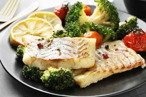 Tasty cod cooked with vegetables served on grey table, closeup Stock Photos