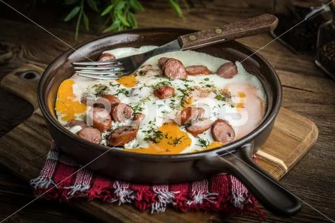 Tasty cooked egg with chopped sausages. Stock Photos