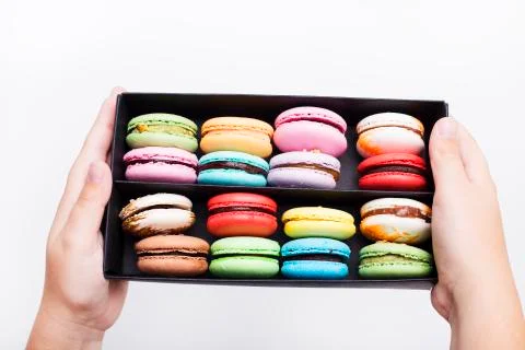 Tasty different colored macarons in black box on white background. 库存照片