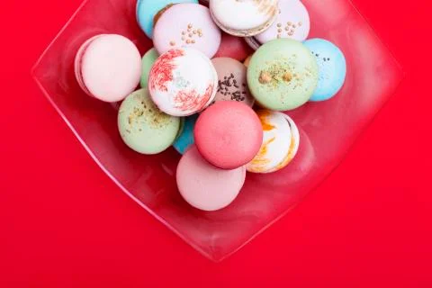 Tasty different colored macarons in  dish  on red background. Фото