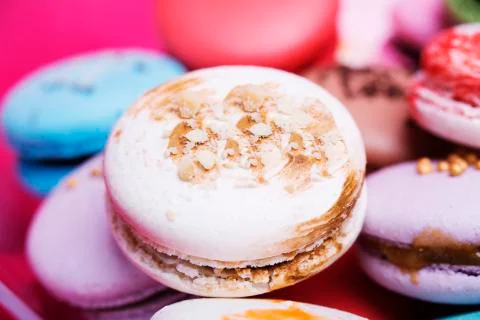 Tasty different colored macarons on red background Фото