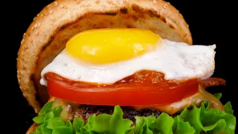 Tasty Egg-Topped Burger with meat and bacon, camera moves from bottom to top Stock Footage 84653027