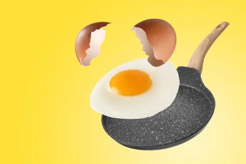 Tasty fried chicken egg with shell falling into frying pan on yellow backgrou Stock Photos