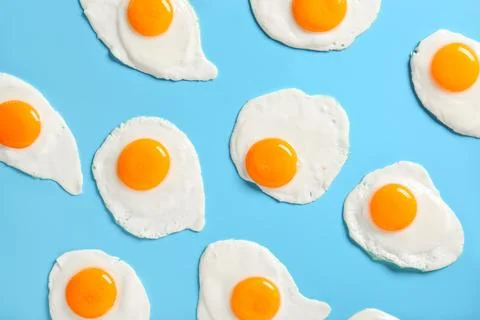 Tasty fried eggs on blue background Stock Photos
