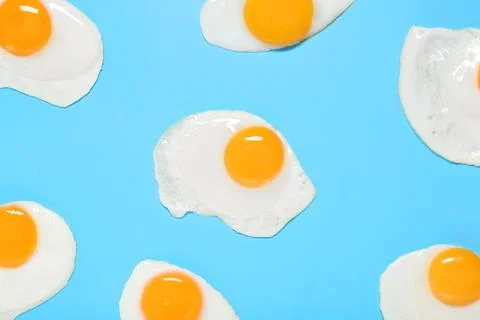 Tasty fried eggs on blue background Stock Photos
