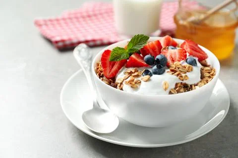 Tasty granola with yogurt and berries served for breakfast on light table Stock Photos