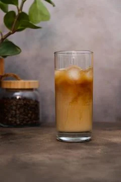 Tasty ice coffee with milk, cold drink in glass in grey background. Stock Photos