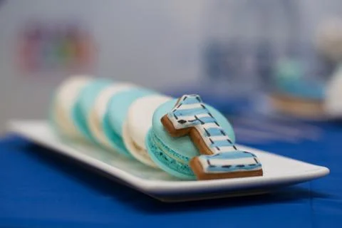 Tasty macaroons and cookie in the shape of the number one lying on the plate. Stock Photos