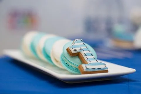 Tasty macaroons and cookie in the shape of the number one lying on the plate. Stock Photos