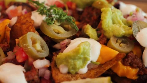 Tasty nachos topped with smashed beef, melted cheese, jalapenos, tomatoes Stock Footage 327858863