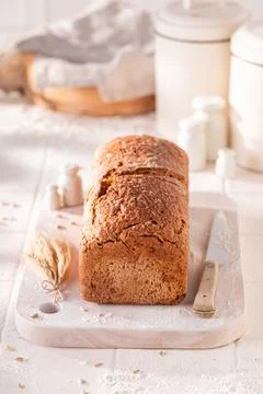 Tasty oat bread baked in a rustic bright kitchen. Stock Photos