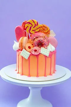 Tasty orange cake with sweets on plain purple background Stock Photos