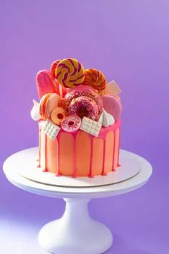 Tasty orange cake with sweets on plain purple background Stock Photos
