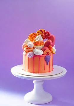 Tasty orange cake with sweets on plain purple background Stock Photos