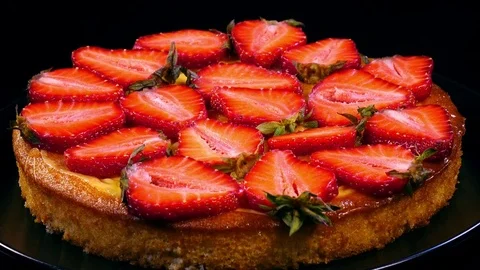 Tasty pie with sliced strawberry rotating on plate against black background 4K 動画素材 78056341