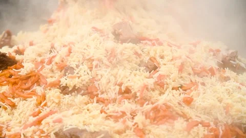 Tasty pilaf in a cauldron on fire in the open air at street food festival Stock Footage 306547074