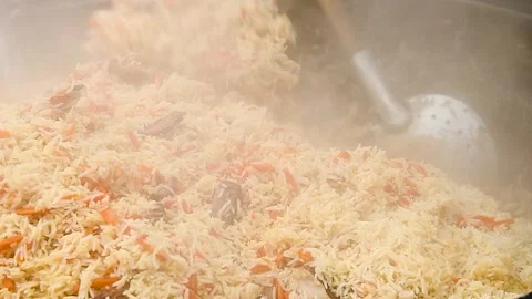 Tasty pilaf in a cauldron on fire in the open air at street food festival Stock Footage 306547081