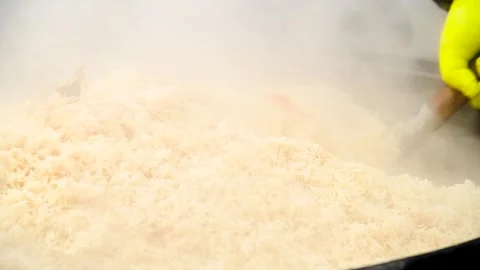 Tasty pilaf in a cauldron on fire in the open air at street food festival Video stock 340065417