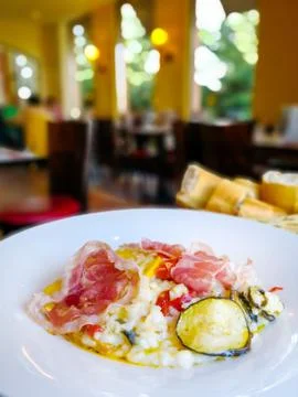 Tasty risotto with ham , fresh herbs vegetables on a white plate Stock Photos