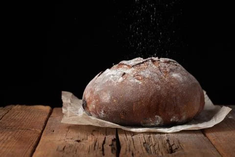 Tasty rustic bread on wooden table on black background with copy space for text Stock Photos