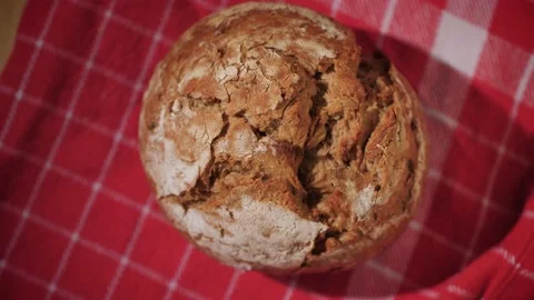 A tasty rustic wholemeal bread bun on a checkered red towel. Stock Footage 145973801