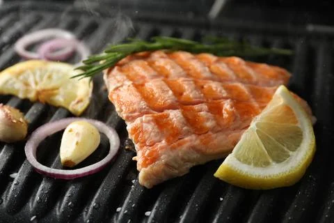 Tasty salmon cooking with rosemary, garlic, onion and lemon on electric gri.. Stock Photos