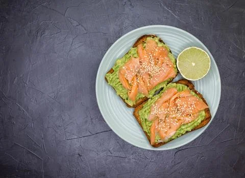 Tasty sandwich with rye bread, avocado and salmon. Gourmet snack Stock Photos