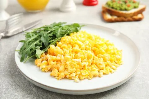 Tasty scrambled eggs with arugula served for breakfast on grey table Stock Photos