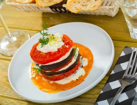 Tasty stack of fried eggplants and tomatoes on spicy sauce served at plate Foto stock