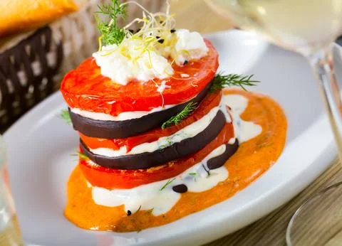 Tasty stack of fried eggplants and tomatoes on spicy sauce served at plate 스톡 사진