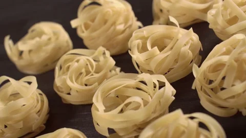 Tasty yellow Tagliatelle pasta rotating on black wooden table close up view from Stock Footage