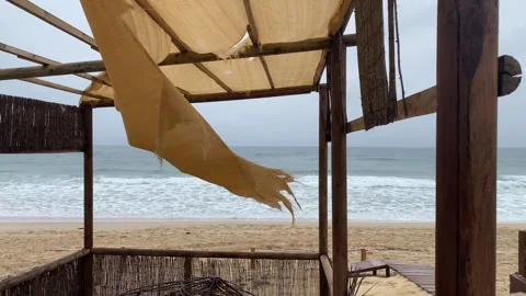 Tattered canopy flutters in the wind, empty beach Stock Footage 304335468