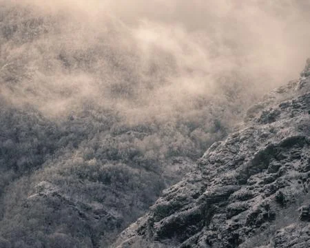 Tattered clouds traverse gorges between snowy mountain Stock Photos