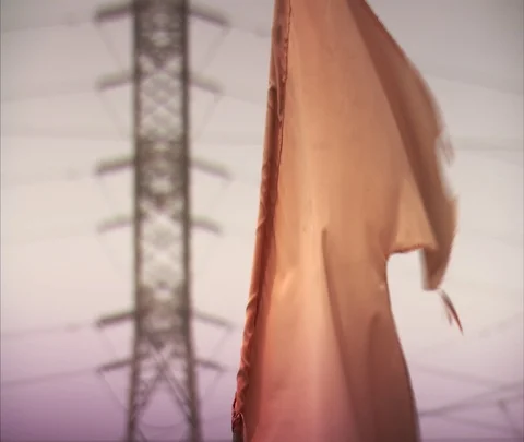 Tattered orange flag blowing in front of transmission towers Stock Footage 86741663