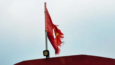 Tattered Vietnamese flag atop rusty vessel fluttering against overcast sky, Hòa Stock Footage 308993979