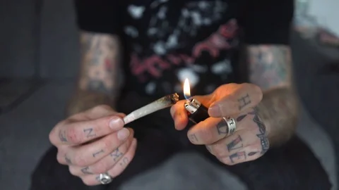 Tattoed hand rolling a marijuana joint smoke Stock Footage 90021907