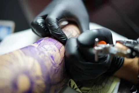 Tattoo artist demonstrates the process of getting black tattoo Stock Photos