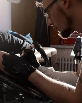 Tattoo artist does the tattoo on his hand man. Closeup Stock Photos