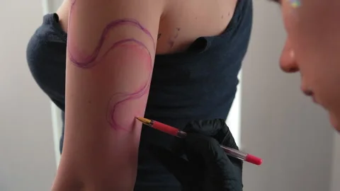 Tattoo artist draws a sketch of an abstract tattoo on a girl Stock Footage 180189953